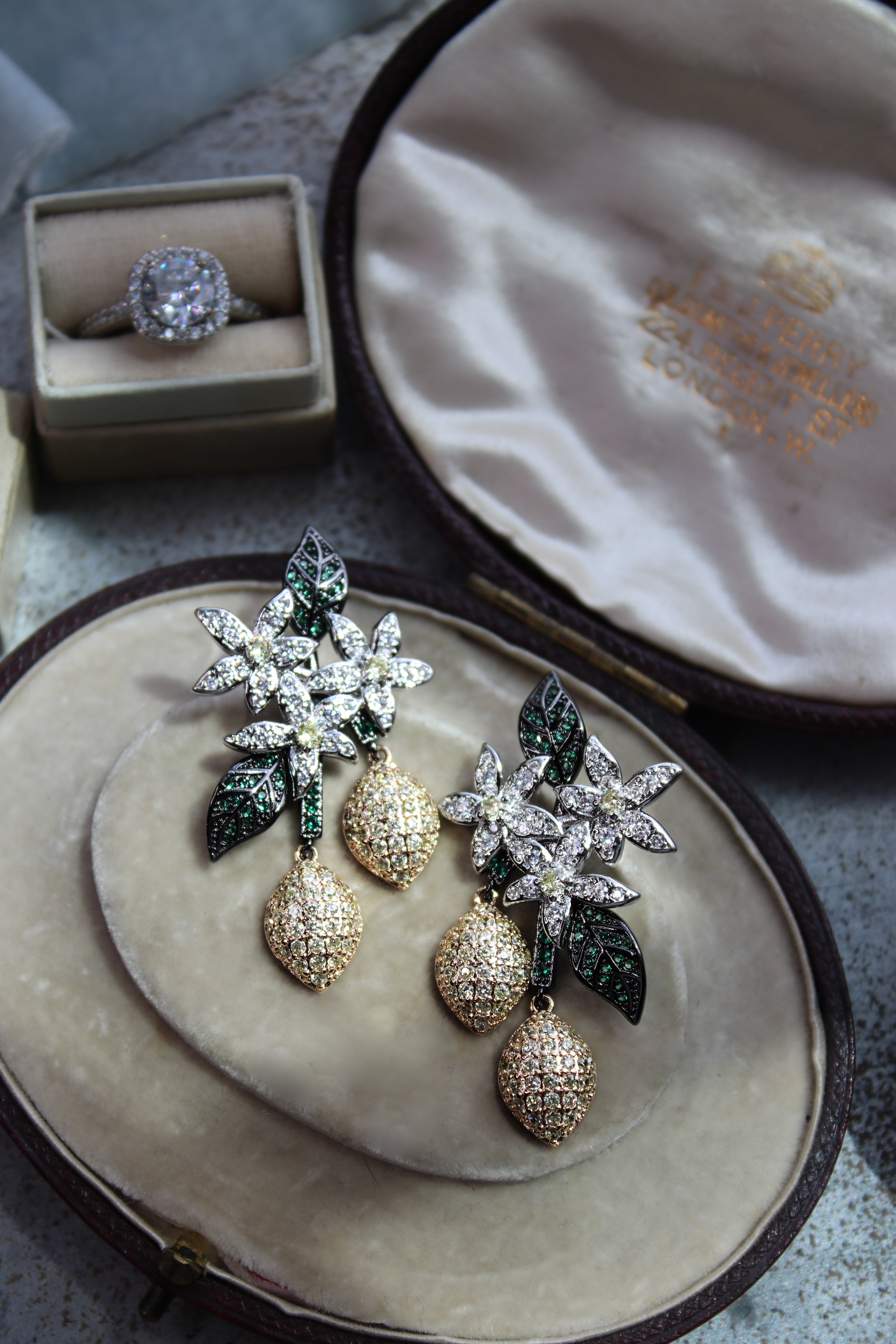 Pair of earrings with Lemons on a jewelry box with a ring in the background.