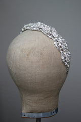 CLARISSA crystal and pearl bridal headband featuring intricate floral and faux pearl elements on a flexible silver base, side view.