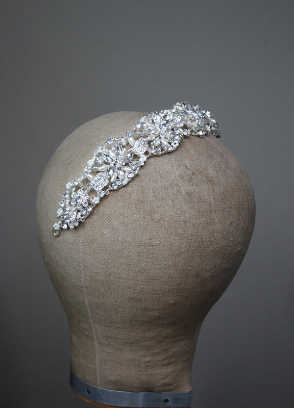 Bridal pearl and crystal headband, CLARISSA design, showcasing sparkling floral and rhinestone details, angled side view.