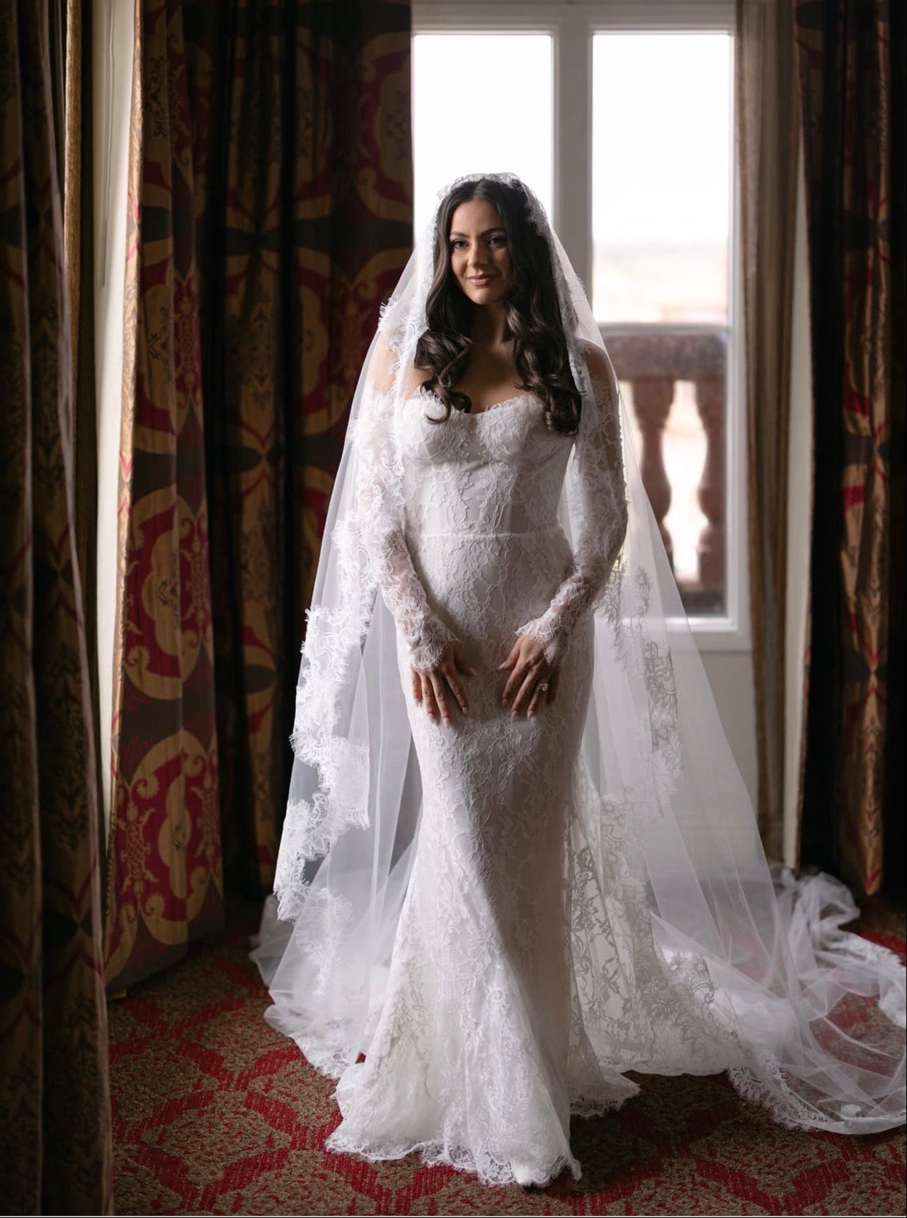 Bride in a Coquette de Versailles cathedral mantilla veil worn forward, French Chantilly lace framing her face 