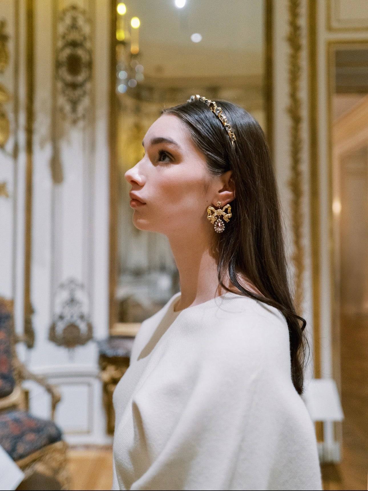 Woman wearing a decorative EDEN LUXE headband and earrings in an elegant interior setting