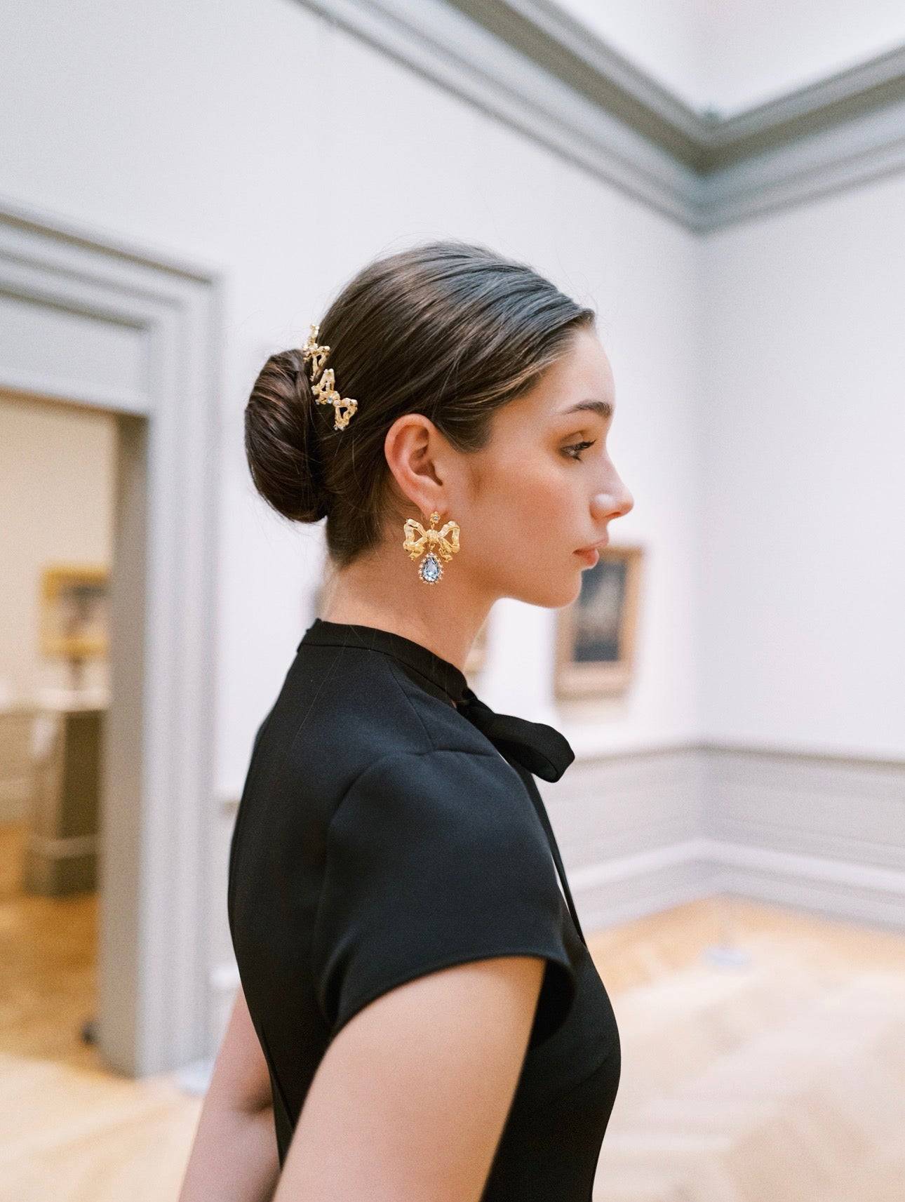 Woman wearing gold earrings in a room with white walls and wooden floors