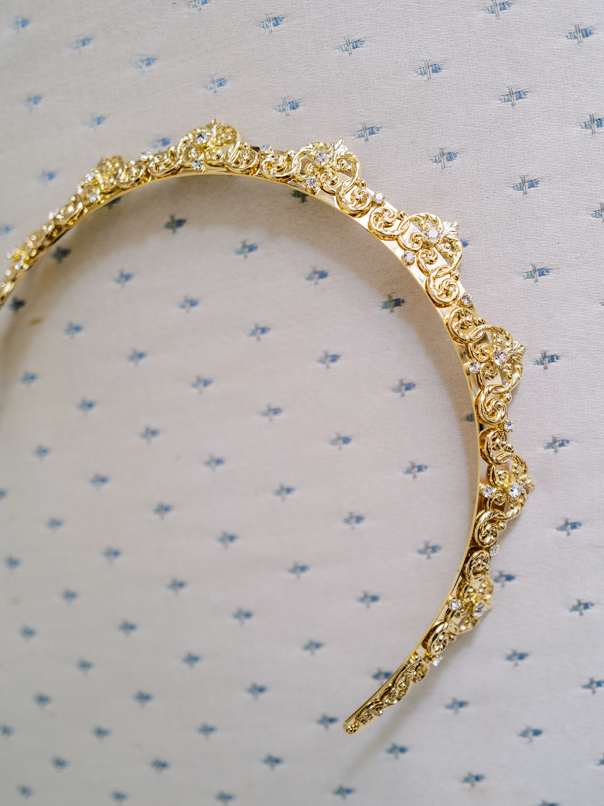 Antoinette Halo Everyday Tiara flat lay on blue-and-cream fabric, gold baroque crystal halo headband and luxury holiday gift for her | EDEN LUXE Bridal