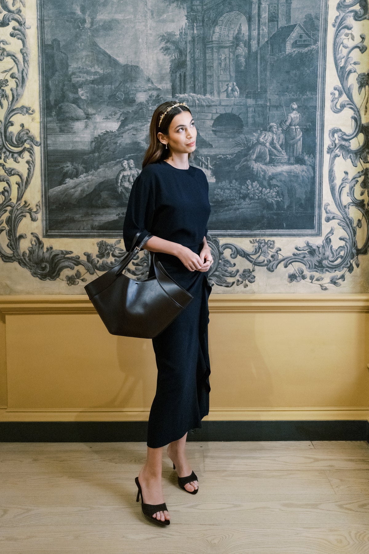 Model in a navy dress wearing the Madame Brillon headband before 18th-century grisaille scenic panels at The Metropolitan Museum of Art, Sophie Kaye x EDEN LUXE Revolution Collection | EDEN LUXE Bridal